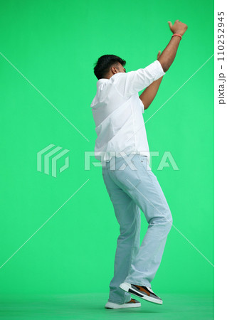 A man in a white shirt, on a green background, standing tall, waving his arms, in profile 110252945