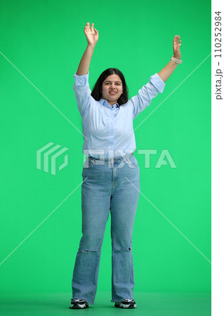 A girl in a blue shirt, on a green background, in full height, waving her arms 110252984