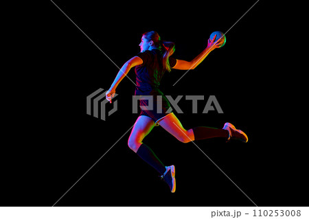 Talented handball player, female sportsman practicing techniques, capturing intensity of sport against black background in neon light. Concept of movement. 110253008