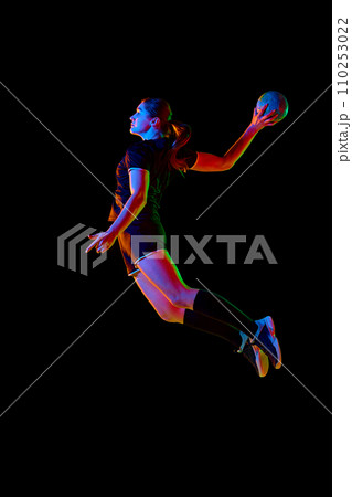 Athletic young woman, sportsman showing handball techniques, emphasizing skill and dedication against black background in neon light. Concept of sport. Athletic young woman, sportsman showing handball techniques, emphasizing skill and dedication against black background in neon light. Concept of sport. 110253022
