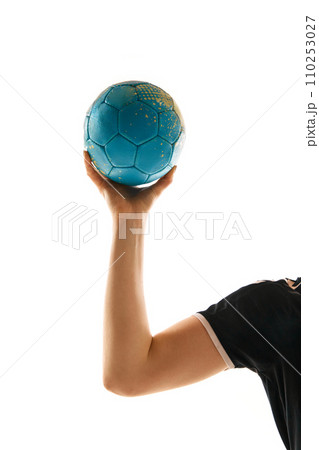 Cropped image of female athlete, professional handball player holding ball in hand against white studio background. Concept of sport. 110253027