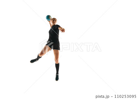 Fit, focused woman engaged in handball drills, displaying determination and focus against white studio background. Concept of sport and training. 110253095