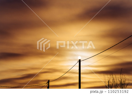 Sun on an electric pole before sunset. Concept of lack of electricity, energy crisis. Mystical sunset on a frosty winter evening. 110253192