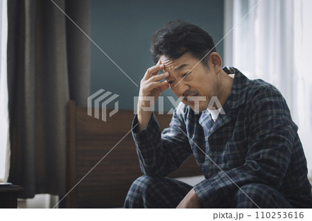 ベッドに座って頭を抱える中年男性 ベッドに座って頭を抱える中年男性 110253616
