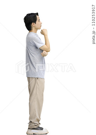 A guy in a gray T-shirt, on a white background, in full height, thinks 110253917