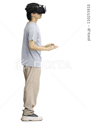 A guy in a gray T-shirt, on a white background, full-length, wearing VR glasses A guy in a gray T-shirt, on a white background, full-length, wearing VR glasses 110253918