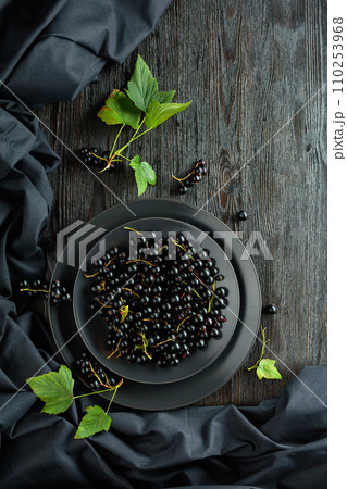 Black currant with leaves on a old wooden table. Black currant with leaves on a old wooden table. 110253968