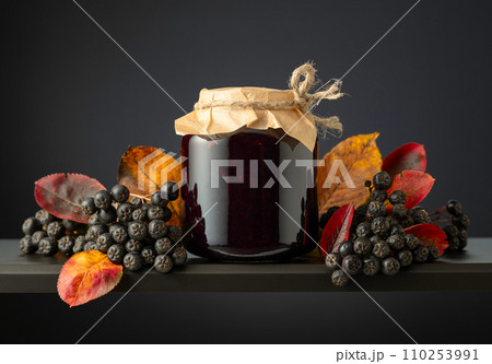 Chokeberry jam and fresh berries with leaves. Chokeberry jam and fresh berries with leaves. 110253991