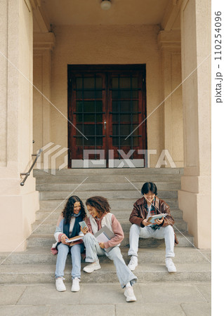 Happy college students having fun using mobile phone together in campus outdoors 110254096