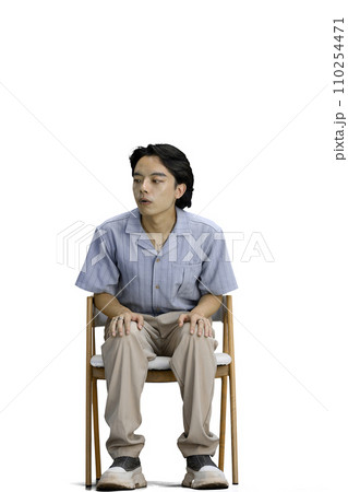 A guy in a blue shirt, on a white background, is sitting on a chair 110254471