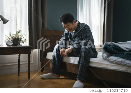 ベッドに座って落ち込む中年男性 ベッドに座って落ち込む中年男性 110254710