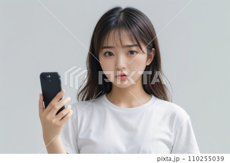 スマートフォンを手に持って怒り気味に驚く日本人美女 110255039