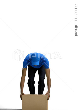 A male deliveryman, on a white background, in full height, put down a box 110255177