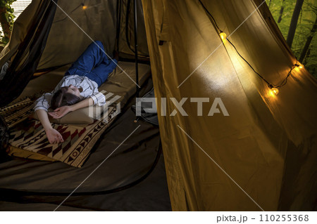 室内キャンプ場のテントでくつろぐ若い女性 110255368