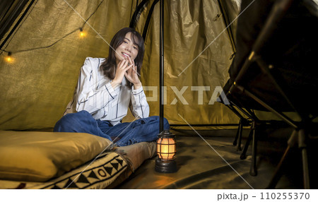 室内キャンプ、テントの中でくつろぐ若い女性 室内キャンプ、テントの中でくつろぐ若い女性 110255370