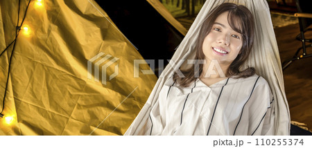 室内キャンプのハンモックでくつろぐ若い女性 110255374