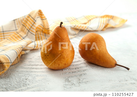 Pears and yellow kitchen towel on white wooden background.. 110255427