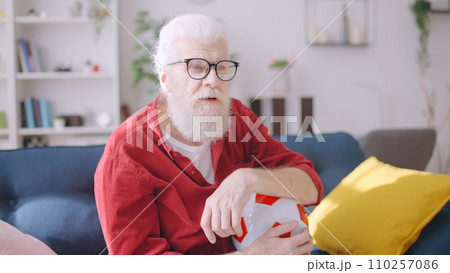 A man in his 60s immersed into a football game on TV, an excited soccer fan waiting for the score 110257086