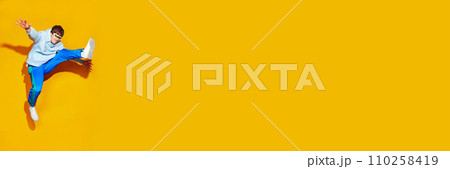 Young attractive man, dressed in comfy sportwear jumping in motion against vivid yellow background with negative space for text. Young attractive man, dressed in comfy sportwear jumping in motion against vivid yellow background with negative space for text. 110258419