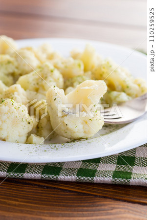 Cooked cauliflower, steamed, in a plate with spices . 110259525