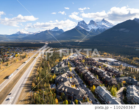 Canmore, Alberta, Canada. Aerial view of Trans-Canada Highway (Highway 1) in a autumn sunny day. The Three Sisters trio of peaks Canadian Rockies mountain range. 110260367