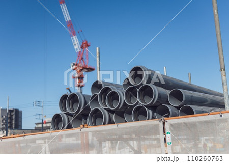 建設現場の資材置場　管路材とクレーン 110260763