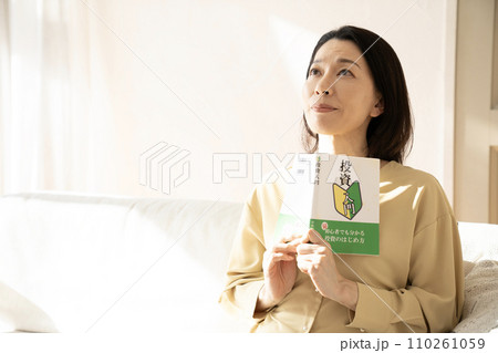投資の本を読んで微笑む女性 投資の本を読んで微笑む女性 110261059