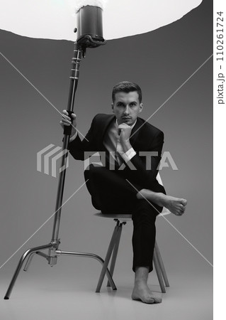 elegant model man in black suit barefoot in photostudio. black and white 110261724