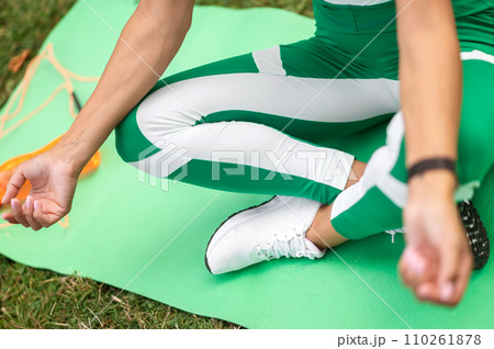 Woman in green sportswear sitting in a lotus pose and meditating Woman in green sportswear sitting in a lotus pose and meditating 110261878