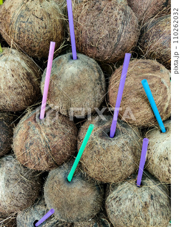 Background of coconut nuts with plastic drinking tubes, vertical frame. Background of coconut nuts with plastic drinking tubes, vertical frame. 110262032