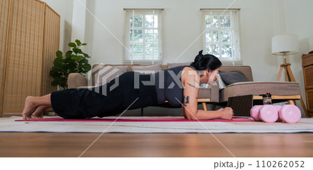 Asian overweight woman doing stretching exercise at home on fitness , online fitness class. Stretching training workout on yoga mat at home for good health and body shape Asian overweight woman doing stretching exercise at home on fitness , online fitness class. Stretching training workout on yoga mat at home for good health and body shape 110262052