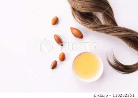 Hairloss concept. Argan seeds, oil and hair isolated on a white background Hairloss concept. Argan seeds, oil and hair isolated on a white background 110262251
