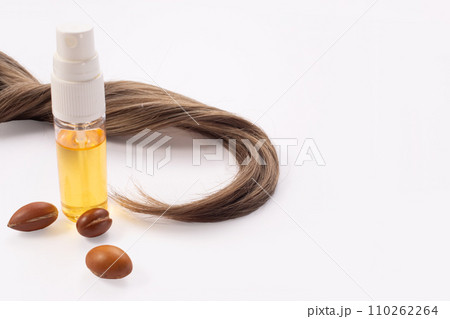 Hairloss concept. Argan seeds, oil and hair isolated on a white background Hairloss concept. Argan seeds, oil and hair isolated on a white background 110262264