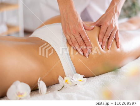 Professional therapist doing anti-cellulite thighs and buttock massage to woman Professional therapist doing anti-cellulite thighs and buttock massage to woman 110269597