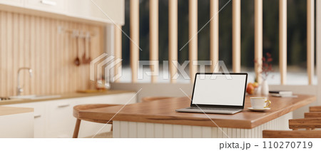 A laptop computer on a wooden kitchen countertop or island in a modern, Scandinavian kitchen. A laptop computer on a wooden kitchen countertop or island in a modern, Scandinavian kitchen. 110270719