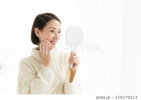 鏡を持ち肌のチェックをする女性 鏡を持ち肌のチェックをする女性 110270813
