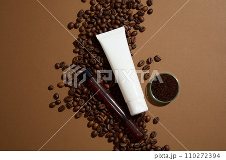White plastic tube with facial moisturizer cream, facial cleanser or mask displayed on brown background with coffee beans and glassware. Top view, cosmetic mockup for design packaging White plastic tube with facial moisturizer cream, facial cleanser or mask displayed on brown background with coffee beans and glassware. Top view, cosmetic mockup for design packaging 110272394