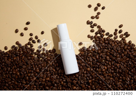 Blank background for advertising cosmetic product with coffee ingredient. Coffee beans decorated with white cosmetic bottle without label for design packaging. Top view Blank background for advertising cosmetic product with coffee ingredient. Coffee beans decorated with white cosmetic bottle without label for design packaging. Top view 110272400