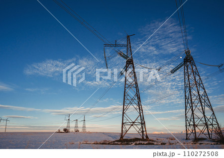 High-voltage power transmission line with towers in field in winter at sunset in the evening High-voltage power transmission line with towers in field in winter at sunset in the evening 110272508