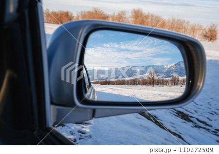 beautiful winter landscape with Tien Shan mountains and trees in field in snow in rearview mirror of car. Concept of festive holiday winter travel in Kazakhstan beautiful winter landscape with Tien Shan mountains and trees in field in snow in rearview mirror of car. Concept of festive holiday winter travel in Kazakhstan 110272509