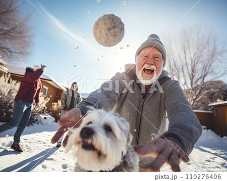 Energetic senior man with a snowball ready to throw, laughing with joy during a snowball fight with friends on a sunny winter day 110276406