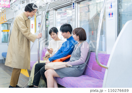スマホを見ながら電車に乗る若い女性と友達　撮影協力「京王電鉄株式会社」 110276689