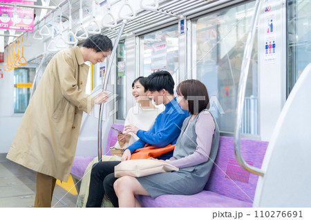 スマホを見ながら電車に乗る若い女性と友達　撮影協力「京王電鉄株式会社」 110276691