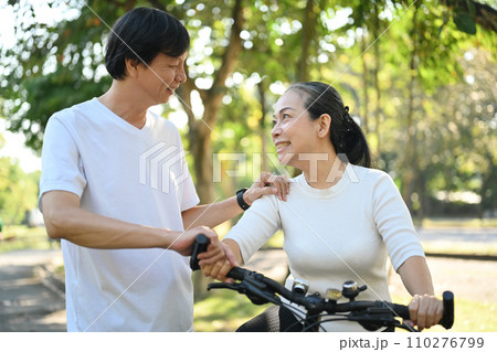 Shot of happy retired couple riding bicycles at summer park. Healthy lifestyle concept. Shot of happy retired couple riding bicycles at summer park. Healthy lifestyle concept. 110276799