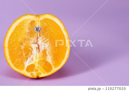 Intimate piercing. Minimal piercing concept. Orange with inserted iron decoration, piercing Intimate piercing. Minimal piercing concept. Orange with inserted iron decoration, piercing 110277020