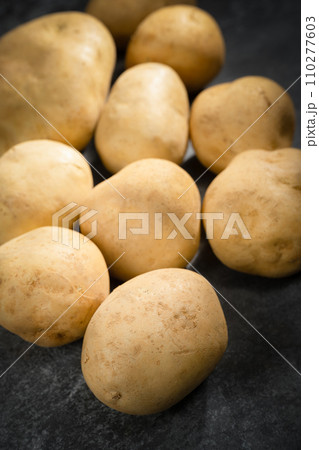 fresh potatoes on a black stone background fresh potatoes on a black stone background 110277603
