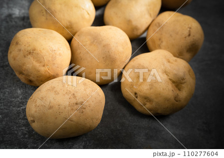 fresh potatoes on a black stone background fresh potatoes on a black stone background 110277604