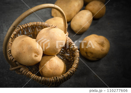 fresh potatoes on a black stone background fresh potatoes on a black stone background 110277606