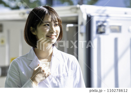 トラックの前に立つ白衣の女性 トラックの前に立つ白衣の女性 110278612