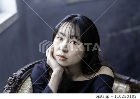ソファーでくつろぐ黒ワンピースの若い女性 110280185